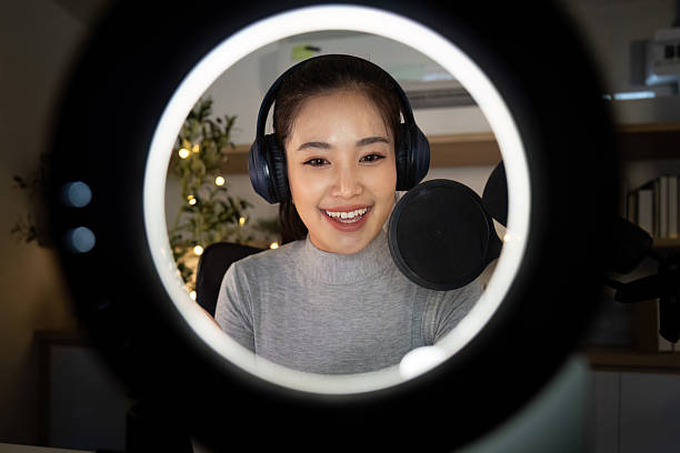 Podcasting. Smiling woman recording her podcast through a ring light setup.