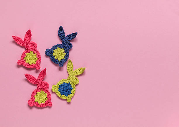 Crochet Easter bunnies on a pink background. Handmade Easter decoration. Top view. Copy space.