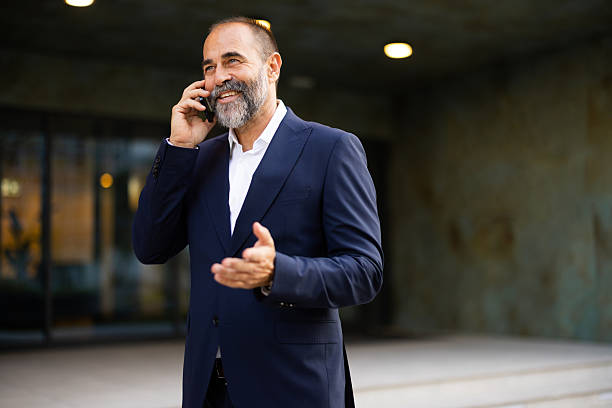 istock Mature businessman talking on phone outside office building 2224604595