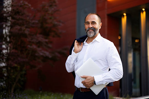 istock Smiling businessman holding laptop and jacket leaving office 2224604640