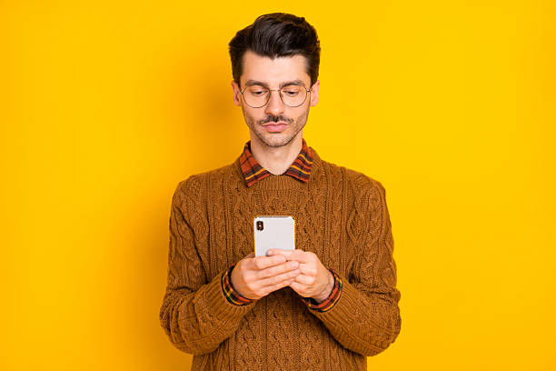 istock Portrait of concentrated man look phone typing comment wear knitted pullover isolated on yellow color background 2224604732