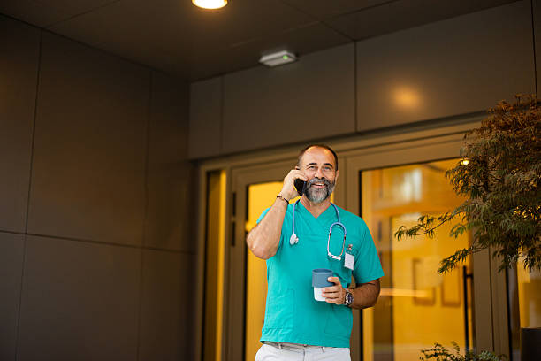 istock Doctor talking on the phone outside hospital while holding coffee 2224604745