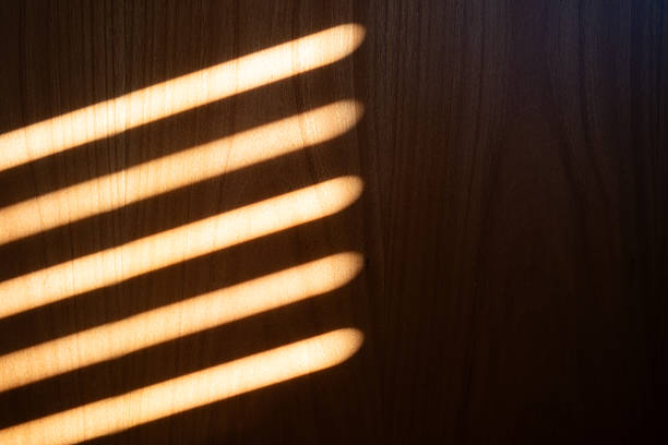 istock Sunlight streaks pattern projected on wooden wall by window roller shutters. Abstract background, no people 2224605142