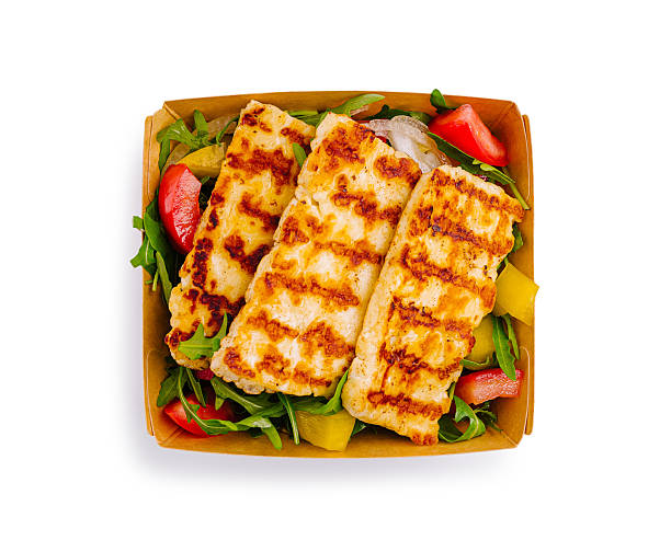 Deliciously grilled cheese is perfectly arranged on top of a colorful salad. Mixed greens accompany fresh tomatoes and bell peppers for a balanced meal. A satisfying dish for cheese lovers.