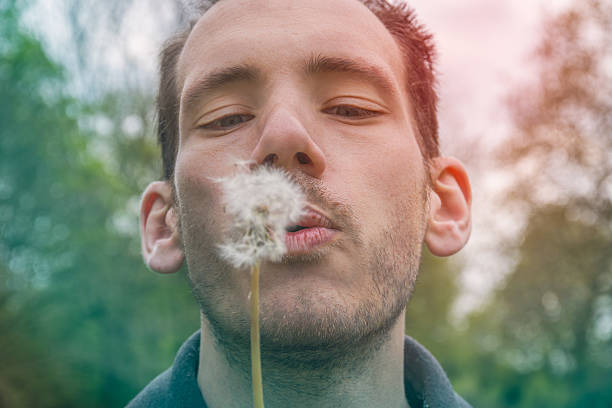 istock A caucasian man blowing dandelion seed head 2224606414
