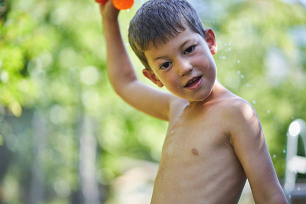Happy boy splashing water outdoors on a sunny summer day