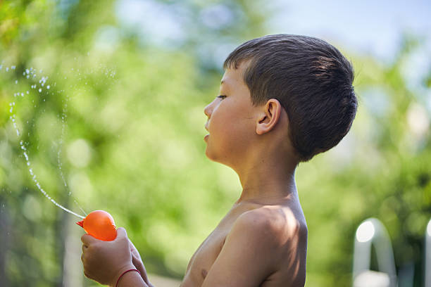 Boy playing outdoors with water balloon on a sunny day