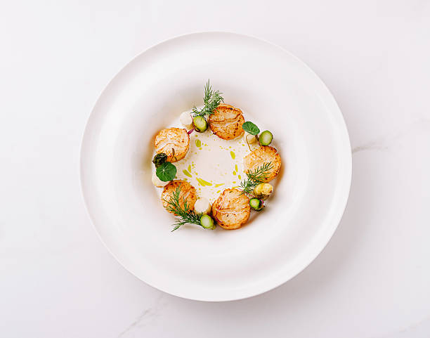 istock Creative culinary presentation with scallops and herbs on a white plate 2224608381