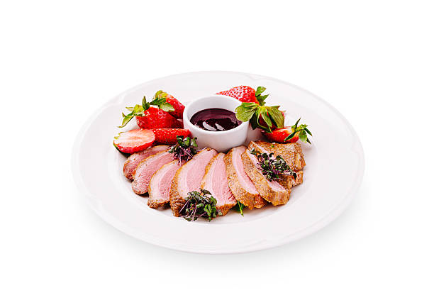 istock Sliced duck breast garnished with strawberries and sauce on white plate 2224608498