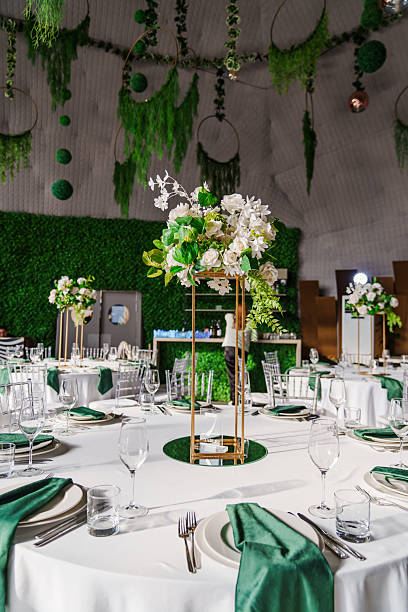 istock flower arrangements, empty glasses, plates with green napkins on a table. 2224608524