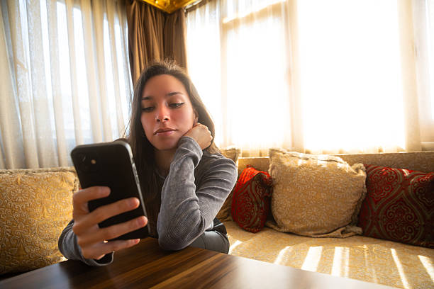 istock Woman relaxing on a sofa while checking her smartphone 2224615633