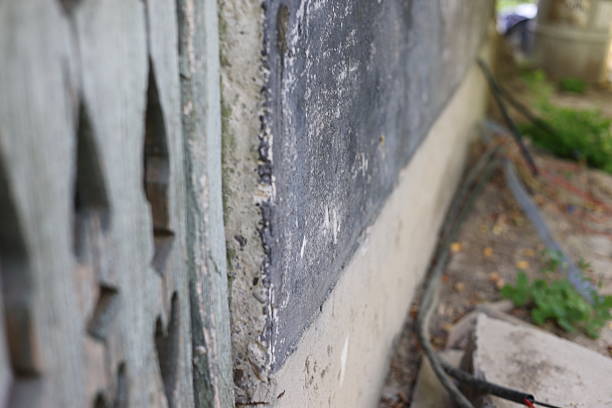 istock Cracked corner of a house wall damaged, with sky and tree branches background 2224615666
