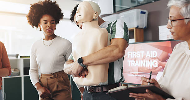 istock First aid, training and people with choking dummy for CPR, abdominal thrusts and life saving procedure in office. Simulation, presentation and demonstration for employee rescue and workplace safety 2224618726
