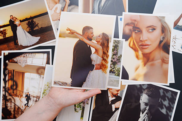 istock women's hands put on the table and show wedding photos. 2224620021