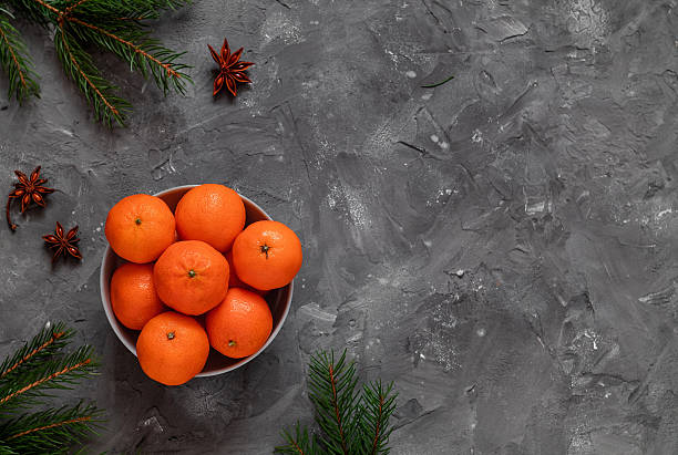 istock Christmas composition with tangerines. Bowl with clementines, fir tree branches and star anise on a grey background. Top view. Copy space. 2224621842