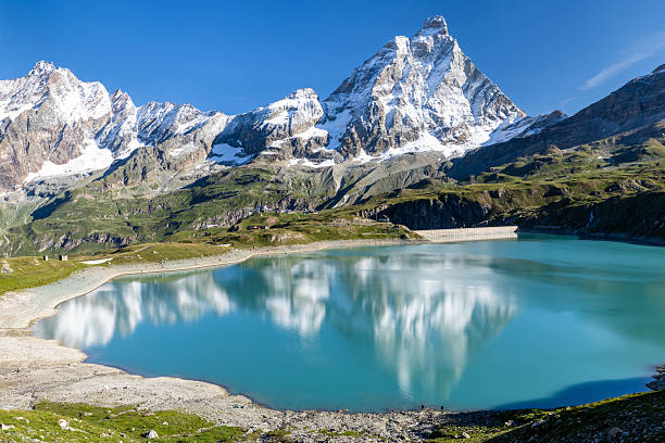 Italy's smallest administrative region, the Aosta Valley, is home to most of the highest peaks in the European Alps. It is so rewarding (and challenging) to walk and climb along its many trails, which overlook some of the most powerful landscapes on earth, including glaciers, green lakes, sharp ridges and majestic sheer cliffs. Here lies the Goillet Reservoir, created by the construction of a dam to produce the cleanest form of energy, hydroelectric power. Facing the lake is one of the most famous mountains on the planet, the Matterhorn, and the Great Wall of other stunning peaks, including Dent d'Herens, along the Italian-Swiss border.