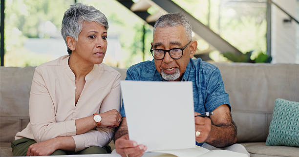 istock Discussion, documents and senior couple on sofa with stress for debt, mortgage or bills repayment. Talk, upset and elderly man with woman for conversation on retirement funds with paperwork in home 2224623088