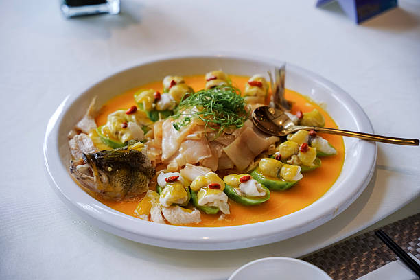 A luxurious Chinese dish. Boiled or steamed fish served artistically on a large white plate with the meat cut into thin slices. The head and tail of the fish are also included in the presentation.