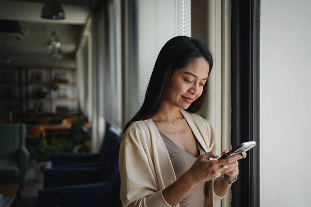 istock Smiling woman using mobile phone in coworking space 2224626883