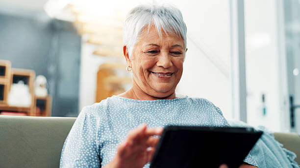 istock Tablet, relax and senior woman on sofa in home learning for online communication, networking or social media. Happy, digital technology and elderly female person in living room reading news on app 2224629944