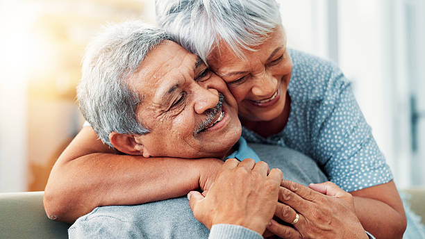 istock Bonding, hug and senior couple in home, smile and commitment for relationship, love and relax in lounge. House, old man and care for woman in living room, embrace and retirement for elderly people 2224629952