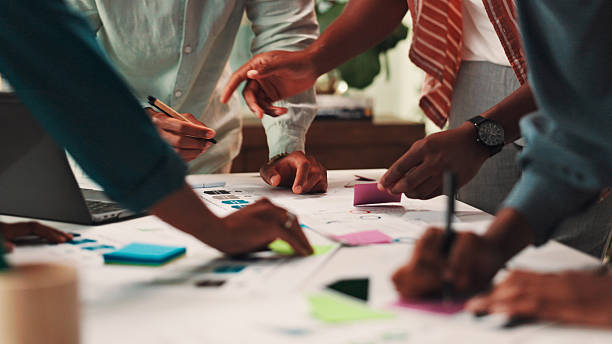 istock People, designers and hands with documents for planning, schedule or meeting together at office. Closeup, group or team working with paperwork or sticky note for sharing ideas on creative strategy 2224630030