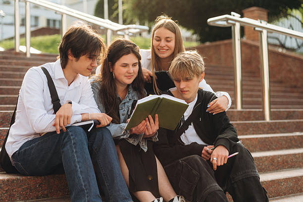 istock Under sunlight, sitting. Group of students are near university together 2224630182