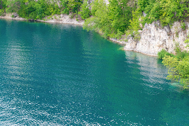 istock Clear blue lake surrounded by green trees and rocky cliffs 2224638599