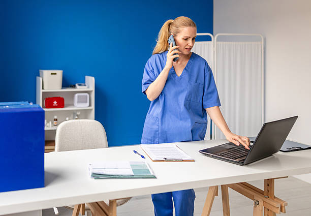 istock Mid adult nurse engages in multitasking by assisting patients while managing tasks on a laptop in a hospital setting 2224639700