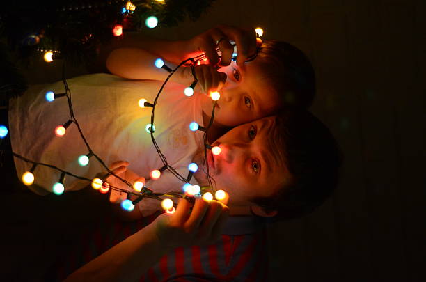 Magical Christmas night: father and son look at the colorful lights of a burning garland