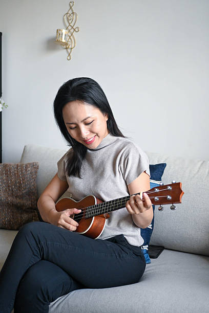 istock Strings of Joy: Woman Learns Ukulele at Home 2224641956