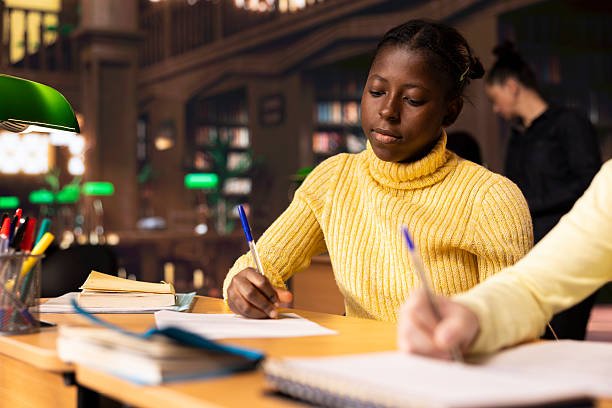 istock Girls classmates brainstorming and writing ideas for a project in school library 2224643953