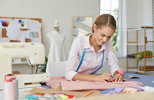 istock Young skillful seamstress woman adjusts fabric with pins while working in sewing workshop. 2224644067