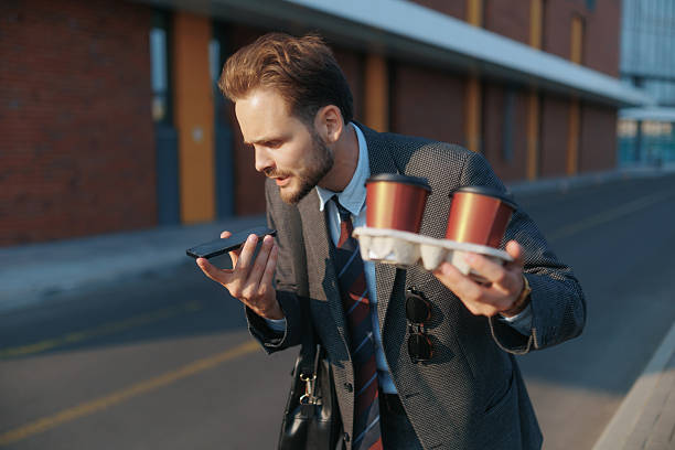 istock Angry young man in suit shouting at phone holding takeaway coffee cups 2224644465