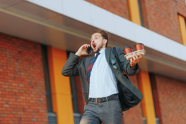 istock Young white collar guy running late, multitasking coffee run and call 2224644492