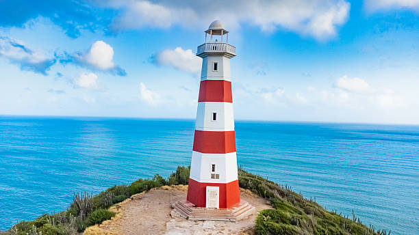 istock Red and White Lighthouse by the Ocean on a Sunny Day 2224645761