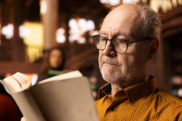 istock Elderly retired person with spectacles having reading hobby at public library 2224646081