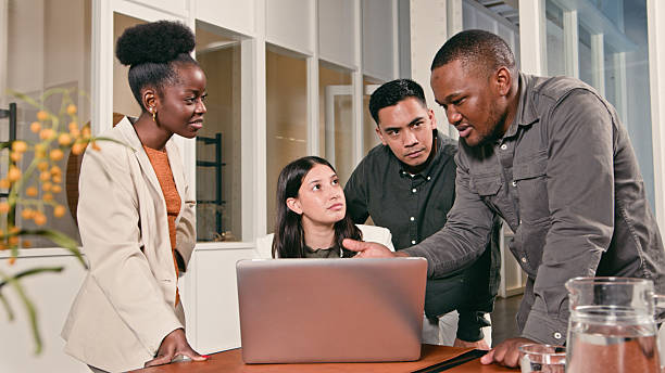 istock Business Team Collaborating in Office with Focus on Discussion Around Laptop 2224648314