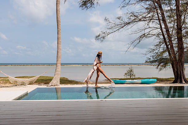 istock Woman walking by the pool on a sandy beach 2224649926