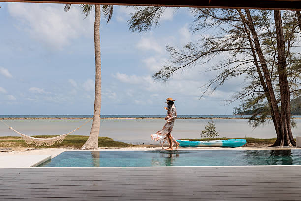 istock Stylish woman strolling by the pool on a sandy beach 2224649960
