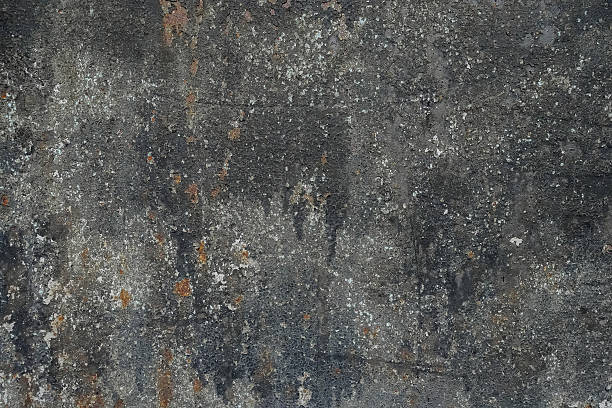 Gray textured vintage background with an image of an old, dilapidated concrete wall with rust inclusions. Traces of dilapidation and old age appeared on the surface