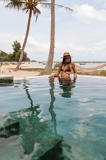istock Woman in bikini relaxing in the pool on a sunny beach 2224651029