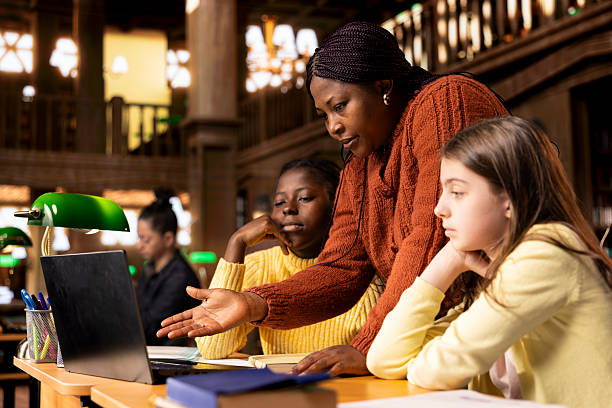 istock Female teacher assisting pupils with class homework and mentoring them 2224652818
