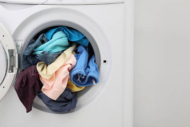 istock Washing machine with laundry near light wall, closeup 2224654340