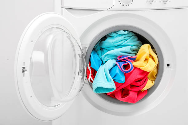 istock Washing machine with laundry near light wall, closeup 2224654444