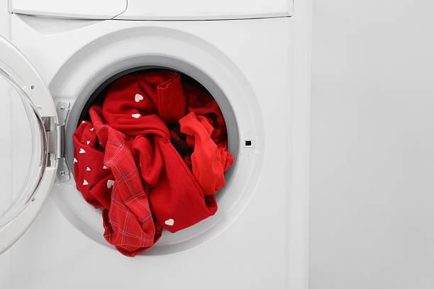 istock Washing machine with laundry near light wall, closeup 2224654458