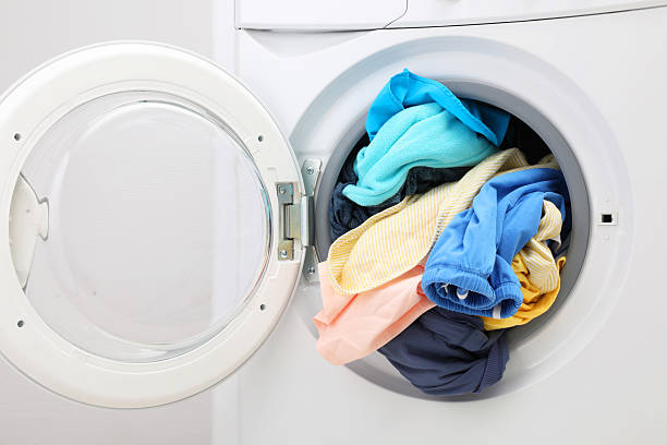 istock Washing machine with laundry near light wall, closeup 2224654480
