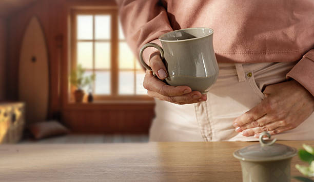 Variety of unfinished earthenware cups stand on a simple wooden shelving unit