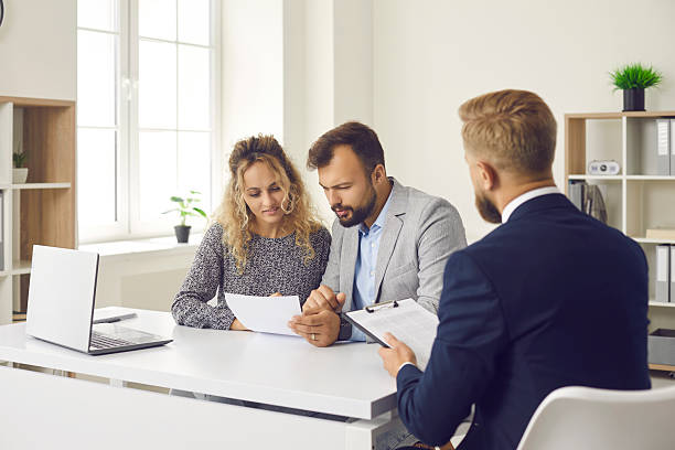 istock Young couple reading some documents sitting at desk in real estate agent's office 2224657221