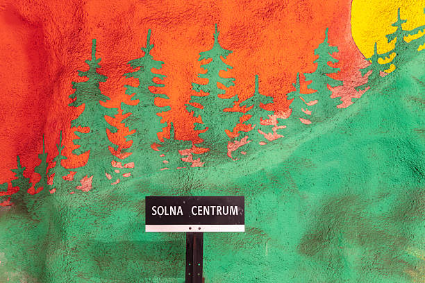 Stockholm, Sweden - June 9, 2025: A colorful mural featuring green trees against an orange and yellow background, with underground station signboard SOLNA CENTRUM in front.